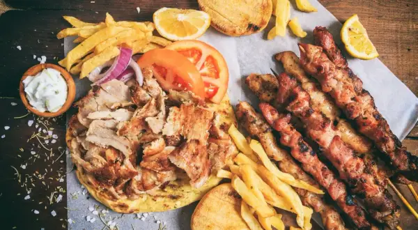 Zapiekanka z kurczakiem gyros, frytkami, pitą, sosami i szaszłykami z kurczaka.