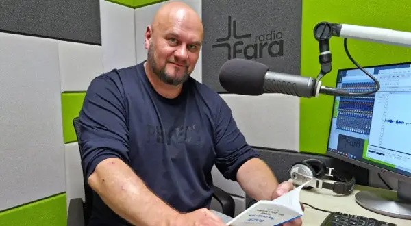 Arkadiusz Łodziewski w studiu Radia Fara, trzymający książkę. Jego życiorys mógłby opowiadać o tej chwili.