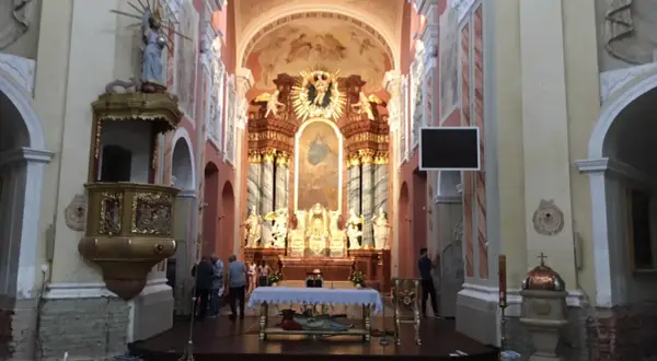 Wnętrze kościoła w Trzemesznie z ołtarzem głównym, amboną i wiernymi.