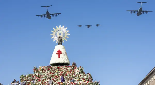 Desfile aéreo de aviones militares sobre una gran ofrenda floral y una imagen de la Virgen del Pilar, celebrando las fiestas del Pilar.