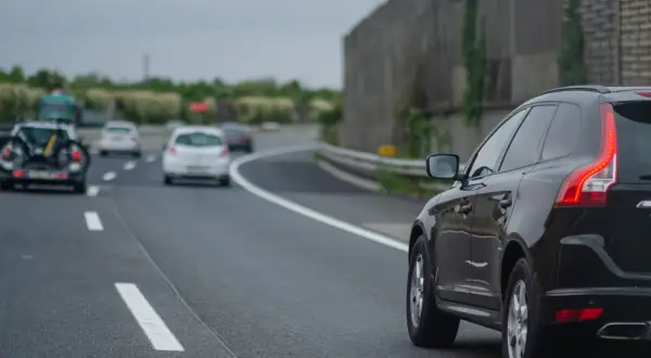 Czarny SUV na autostradzie, obok białe samochody. Kiedy można wyprzedzać z prawej strony? Gdy lewy pas jest wolny, a prawy służy do wyprzedzania.