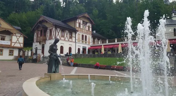 Fontanna i rzeźba w centrum, z pięknymi budynkami w tle. To jedne z wielu atrakcji Szczawnicy.