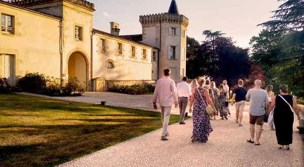 Un groupe de personnes se promène sur le chemin menant au **château Toulouse Lautrec** au coucher du soleil.