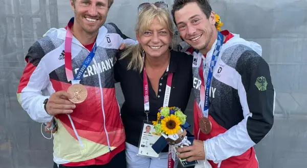Tatjana Pokorny mit zwei Medaillengewinnern des Team Deutschland bei den Olympischen Spielen in Tokio.
