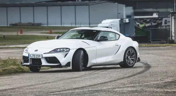 Biała Toyota GR Supra na torze, zostawiająca ślady opon.