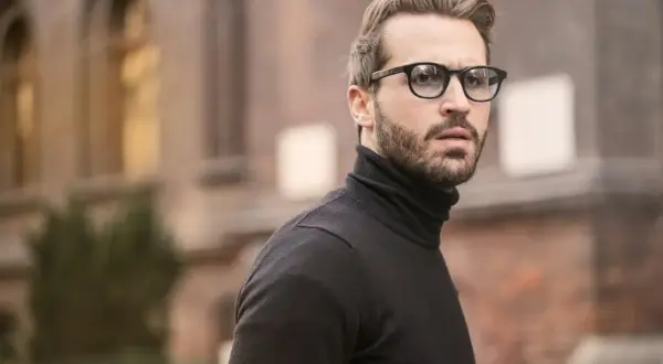 Mann mit Brille und Bart, dessen old money style herren haare perfekt sitzen.