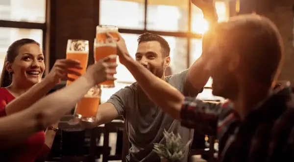 Uśmiechnięci ludzie wznoszą toasty piwem w jednym z najlepszych pubów w Warszawie.