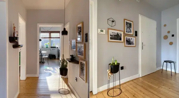Flur mit Holzboden und grau gestrichenem Wanddesign. Bildergalerie und Pflanzen zieren die Wände.