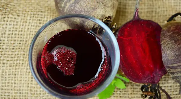 Szklanka z zakwasem buraczanym obok świeżych buraków. Zastanawiasz się, jak długo można trzymać zakwas buraczany w lodówce?