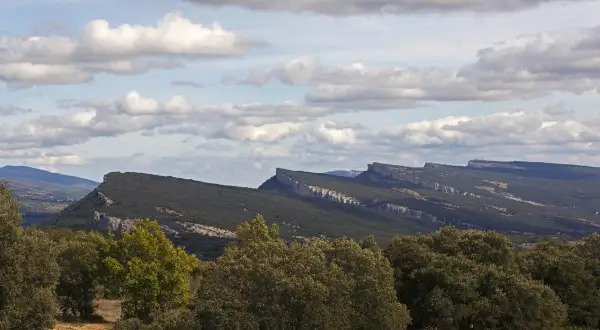 Paisaje montañoso con formaciones rocosas afiladas, típico de fotos de ojo Guareña. Nubes blancas y cielo azul.
