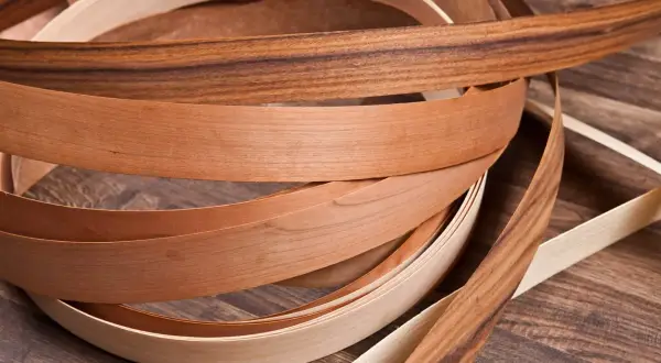 Nastri di impiallacciatura in legno di diverse tonalità, con un effetto plastica che ne esalta la texture naturale.
