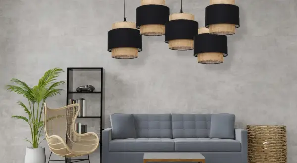 Pięcioramienna lampa pająk boho z abażurami z plecionki i czarnego materiału nad szarą sofą.