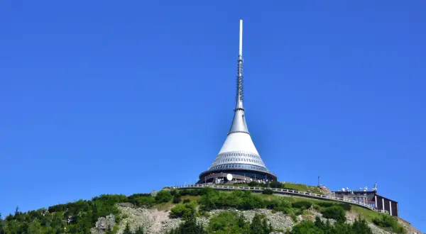 Wieża telewizyjna na górze Ještěd, jedna z głównych libereckich atrakcji, góruje nad zielonymi wzgórzami.