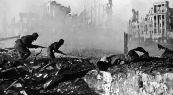 Soldater kämpar i ruiner. En fallen soldat ligger framför dem. Detta är en bild från slaget om Stalingrad, som idag heter Volgograd.