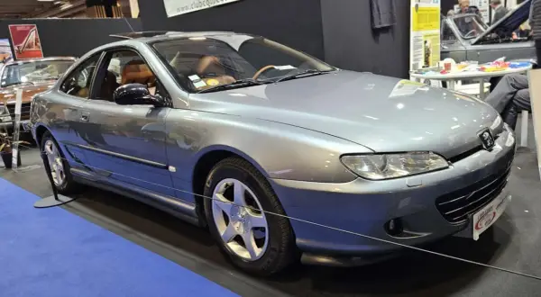 Elegancki, srebrny Peugeot 406 coupe z brązową tapicerką, prezentowany na wystawie.