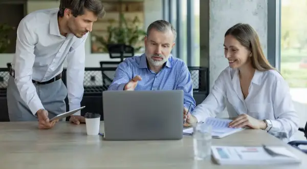 Professionisti discutono su come tutelarsi per affittare un negozio, analizzando contratti al computer.