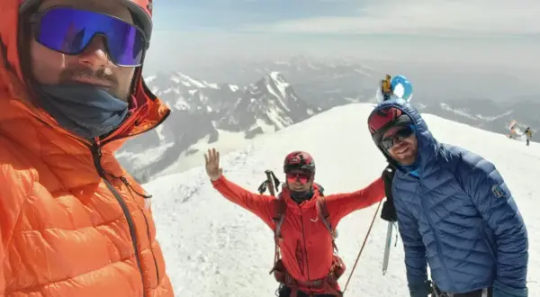 Trzech alpinistów na szczycie Mont Blanc cieszy się widokiem.