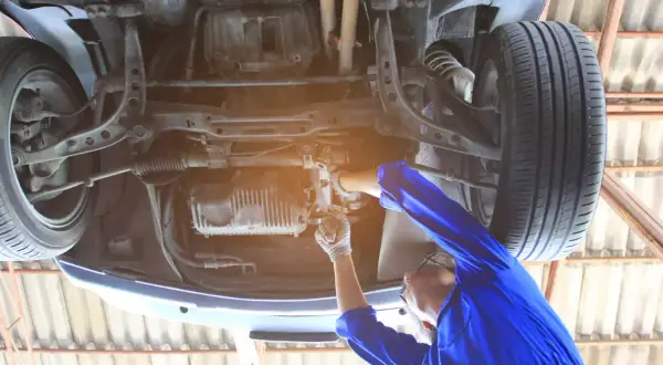 Mechanik reguluje przekładnię kierowniczą, aby usunąć luz na śrubie regulacyjnej. Naprawa zawieszenia samochodu.