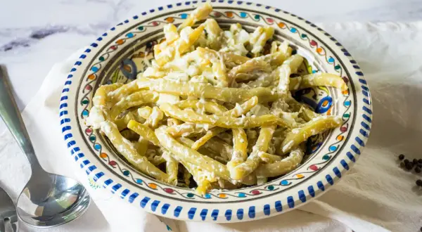 Ein cremiger Bohnensalat mit Sahne, serviert in einer bunten Schüssel. Ein leckeres Gericht, das zum Genießen einlädt.
