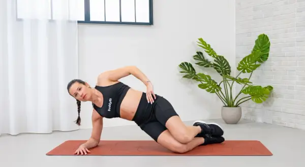 Donna in posizione di plank laterale, con un movimento di circonduzione del busto per rafforzare gli obliqui.