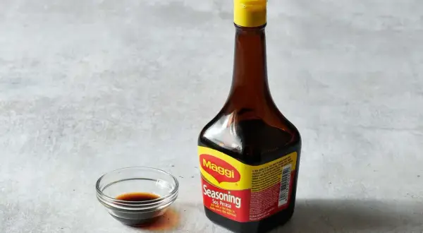 Butelka Maggi i miseczka z ciemnym płynem. Czy sos sojowy można zastąpić maggi?