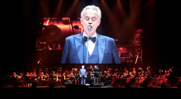 Andrea Bocelli w Gdańsku na koncercie z orkiestrą. Wokalista w garniturze na wielkim ekranie.