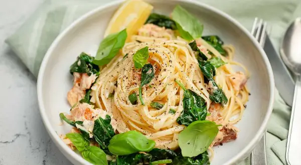 Krämig pasta med lax och spenat, toppad med färsk basilika och en citronklyfta. Smaken påminner om en mild citrusfrukt ugli.
