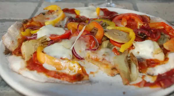 En pizza med surdegsbotten, toppad med mozzarella, paprika, tomat, rödlök och kronärtskocka.