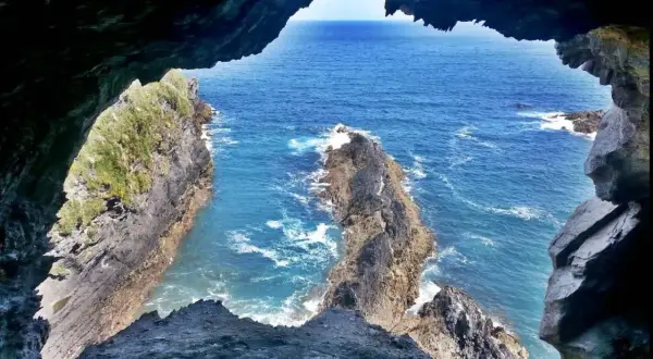 Vista desde la Cova da Doncela hacia el mar azul y acantilados rocosos.