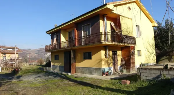 Casa gialla con balcone e vista collinare, un esempio di case economiche in campagna.