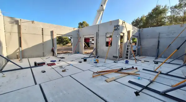 Construcción de una casa prefabricada en Madrid. Se ven paneles de hormigón, puntales y herramientas.