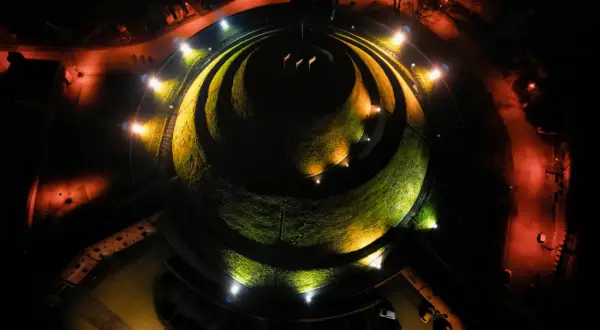 Nocne oświetlenie Kopca Kościuszki tworzy magiczną atmosferę. Kręte ścieżki i zieleń kopca lśnią w blasku reflektorów.