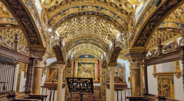 Interior de una capilla ricamente decorada con techos abovedados dorados y azules, pinturas y un altar. Caminos de pasión que invitan a la contemplación.