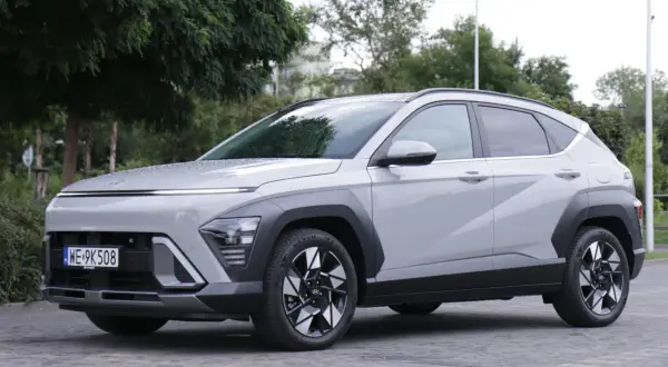 Nowe Hyundai Kona opinie: szary SUV z nowoczesnym designem, zaparkowany na bruku, otoczony zielenią.