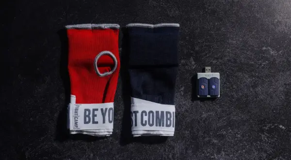 Red and navy hand wraps with "BE YOUR BEST COMBAT" text, and a USB sensor for a boxing match train.