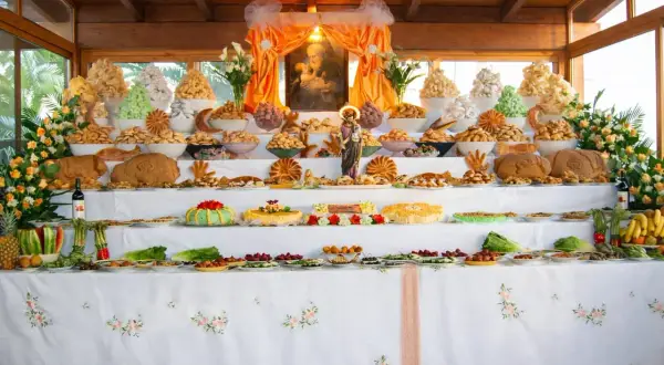 Un'abbondante tavolata ricca di dolci, pani e frutta, che celebra le tradizioni italiane con un'esposizione che ricorda un altare votivo.