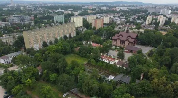 Widok na osiedle mieszkaniowe i kościół, przypominający o historii Krakowa.