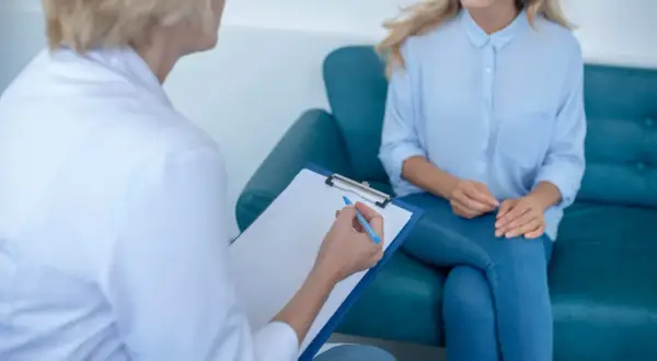 Lekarz podczas rozmowy z pacjentką, notuje na kartce. Trwa diagnoza nozologiczna.