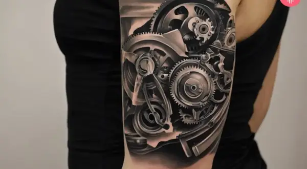 Tatuaż mechanicznej ręki z widocznymi zębatkami i elementami maszynowymi.