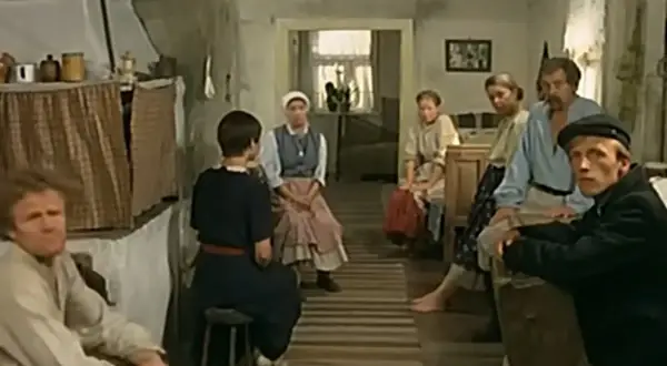Scena z filmu "Znachor", gdzie nagrywali w wiejskiej chacie. Ludzie siedzą w skromnym wnętrzu, czekając na pomoc.