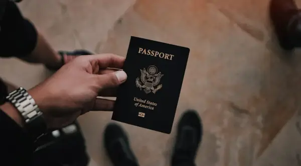 Dłoń trzyma czarny paszport USA. Czas na złożenie wniosku o paszport i rozpoczęcie podróży.