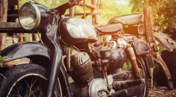 Detalle de una moto antigua, lista para restaurar. Su motor y chasis muestran el paso del tiempo, esperando una nueva vida.