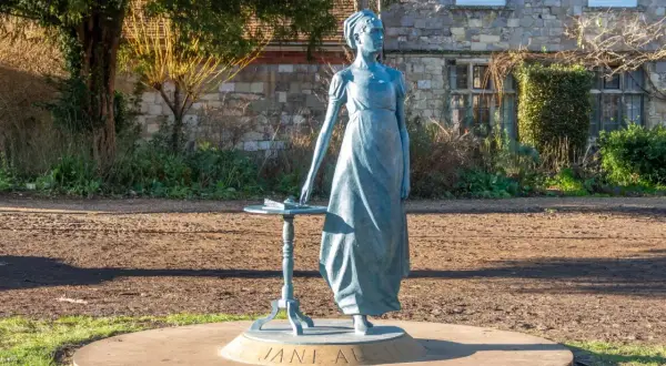 Pomnik Jane Austen, autorki słynnych powieści, stoi przy stoliku z książką.