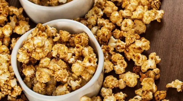 Dwie białe miseczki pełne chrupiącego popcornu karmelowego, idealnego na filmowy wieczór.