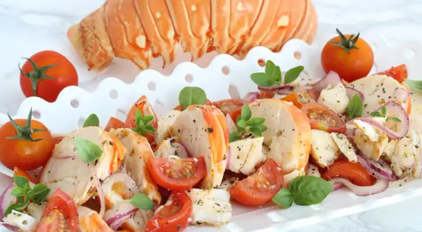 Aragosta alla catalana, un piatto fresco con code di aragosta, pomodorini, cipolla rossa e basilico, guarnito con una coda intera.