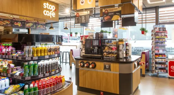 Wnętrze kawiarni Stop Cafe z ladą, ekspresem do kawy, półkami z napojami i przekąskami.