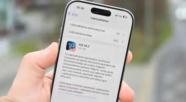 Dłoń trzyma iPhone'a z otwartym ekranem aktualizacji iOS 18.2.