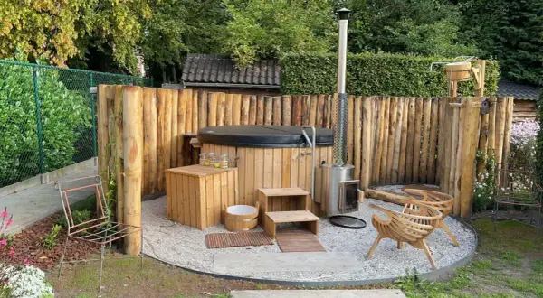 Gemütliche whirlpool ecke im garten gestalten: Holzzaun, Hot Tub, Holzofen, Sitzgelegenheiten und Holzbottich schaffen eine entspannende Oase.