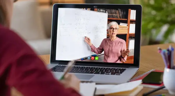 Nauczycielka tłumaczy matematykę na lekcji zdalnej na ekranie laptopa.