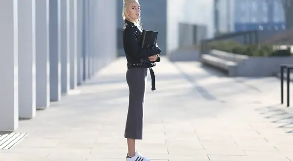 Elegancka kobieta w skórzanej kurtce i ołówkowej spódnicy, prezentująca stylowe adidas superstar stylizacje.
